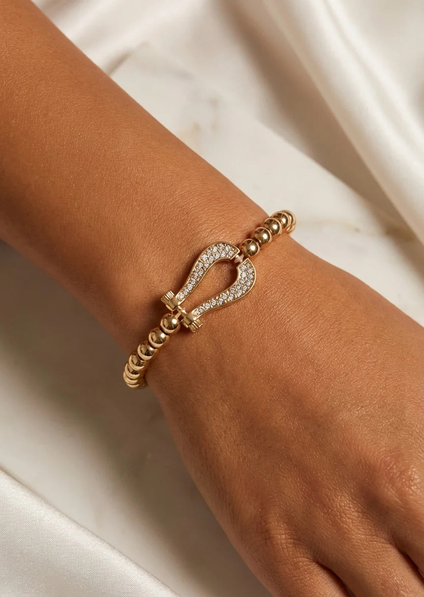 Gold bead stretch bracelet with a cristal horseshoe